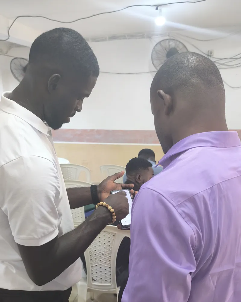 Deux collègues penchés sur un même téléphone, dans les locaux de Douala