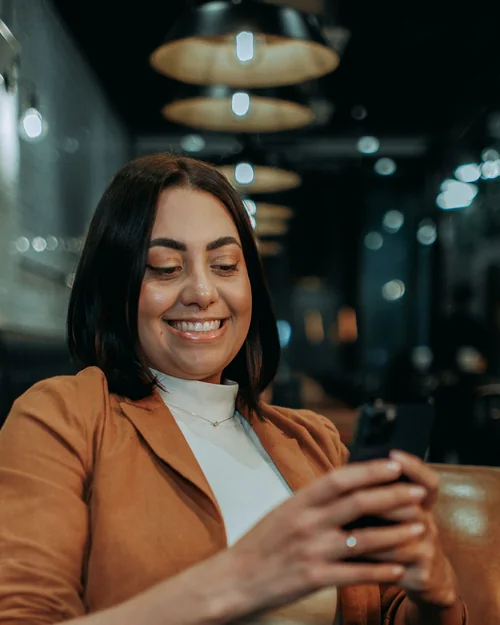 Une entrepreneure souriante, téléphone en main, en fin de journée